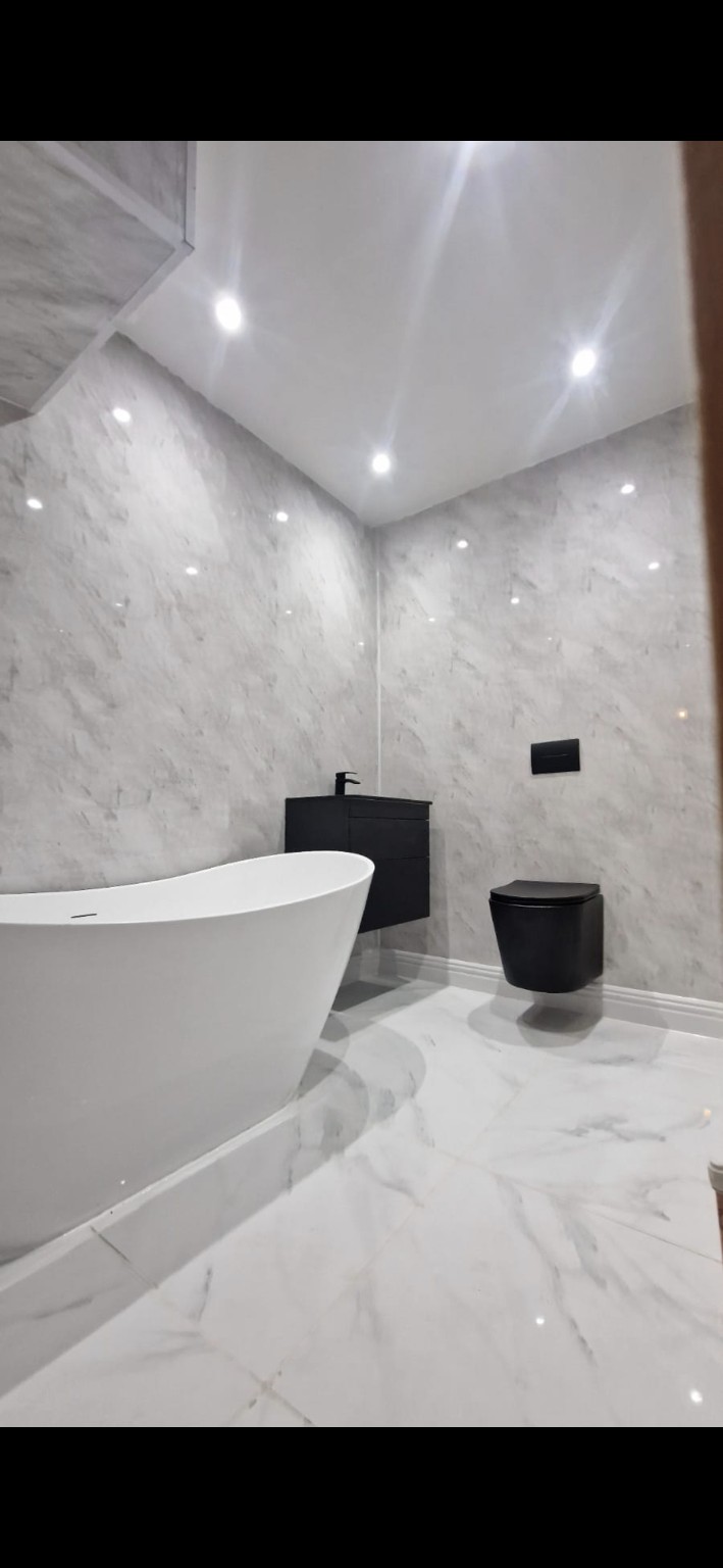 Modern bathroom with freestanding bath, wall panels and black fittings