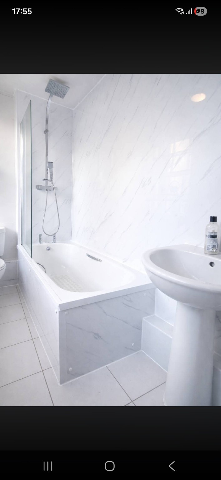 Bright bathroom with bath, shower and marble-effect wall panels